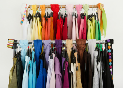 Close up on color coordinated clothes on hagers in a store.